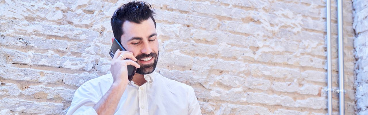 Hombre hablando por teléfono con portátil