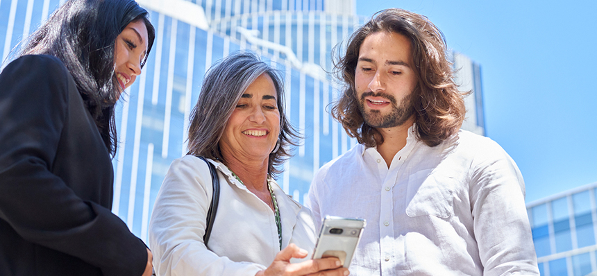 Tres compañeros de trabajo mirando la pantalla de un teléfono